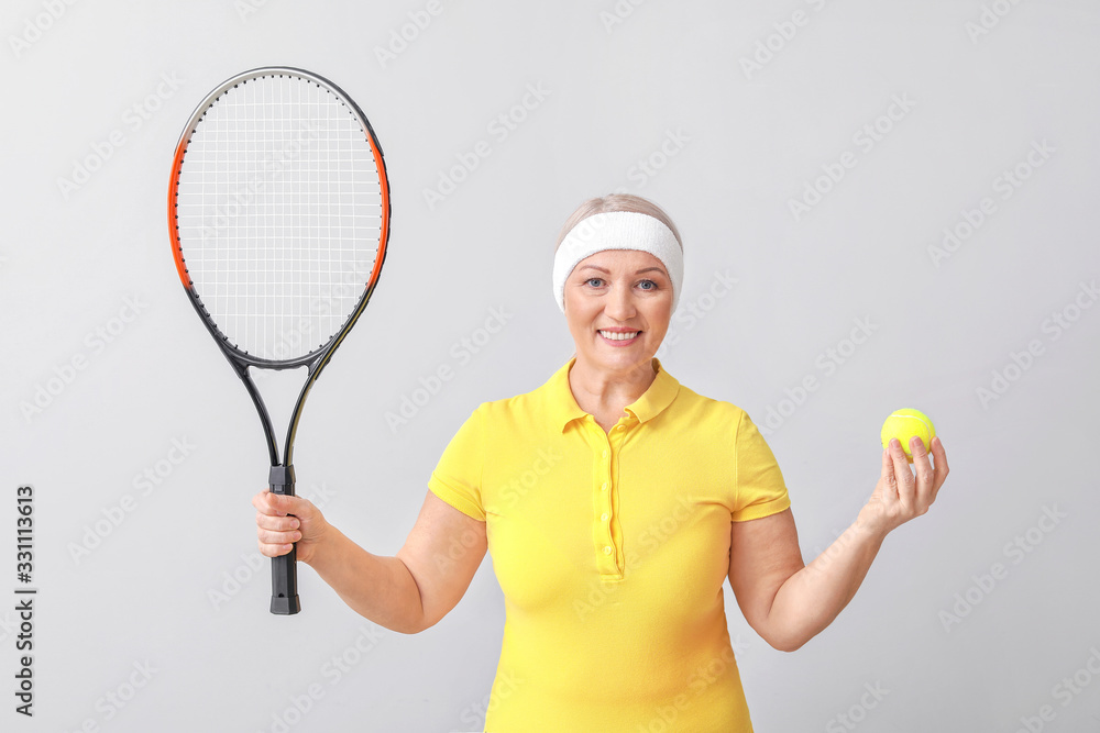 Mature female tennis player on light background