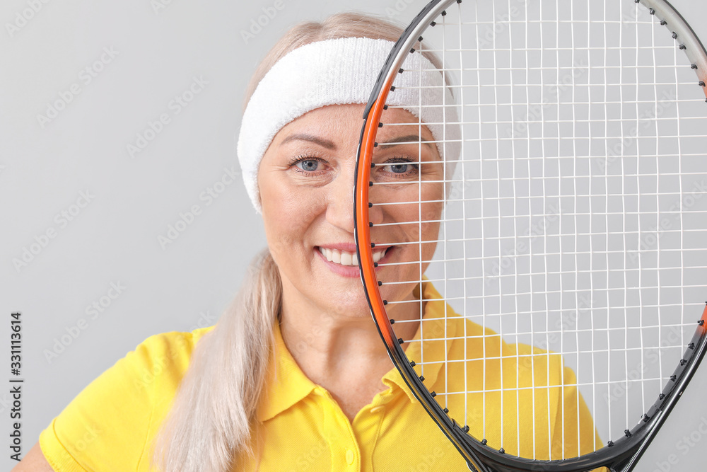 Mature female tennis player on light background