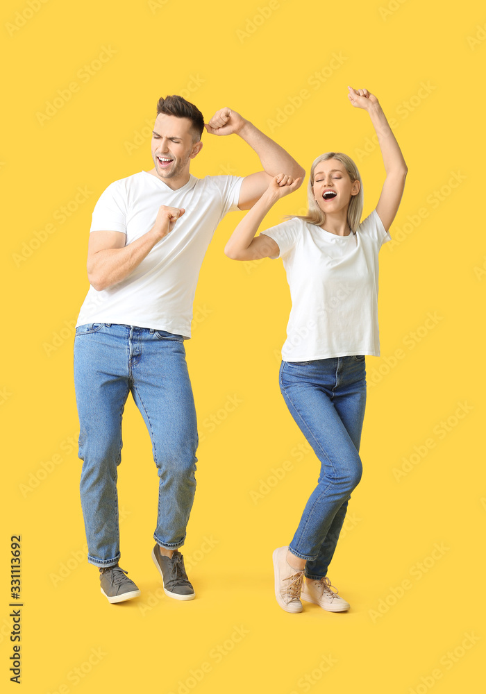 Happy dancing young couple on color background