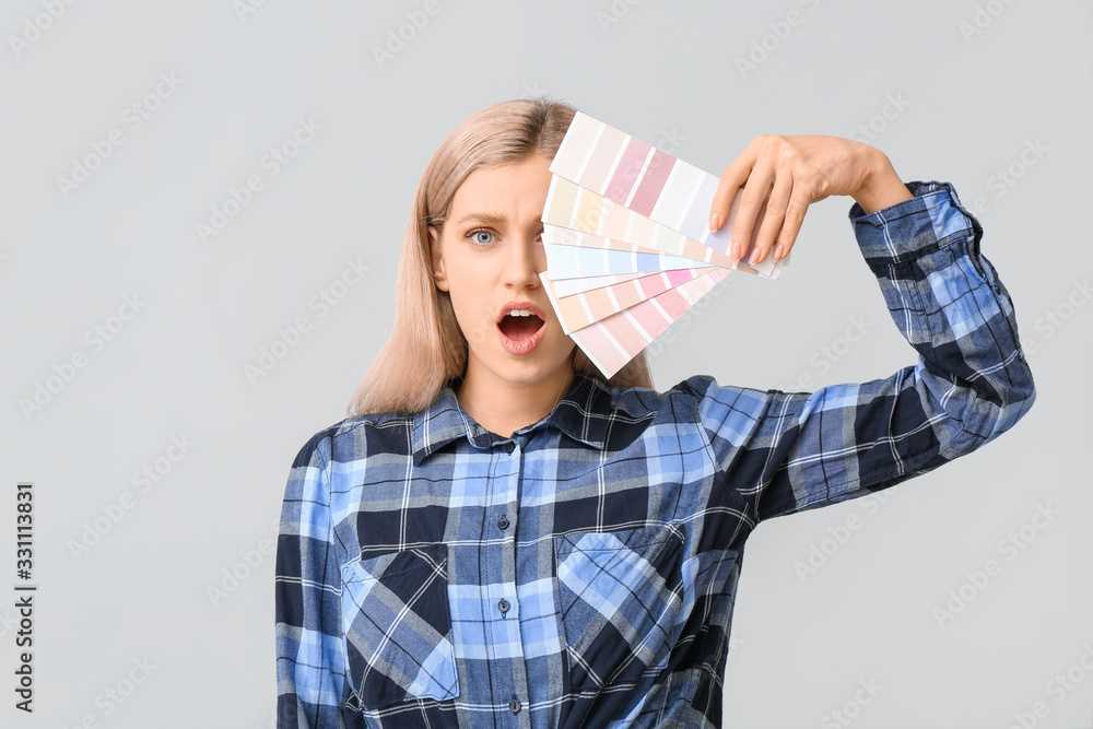 Shocked woman with color swatches on grey background