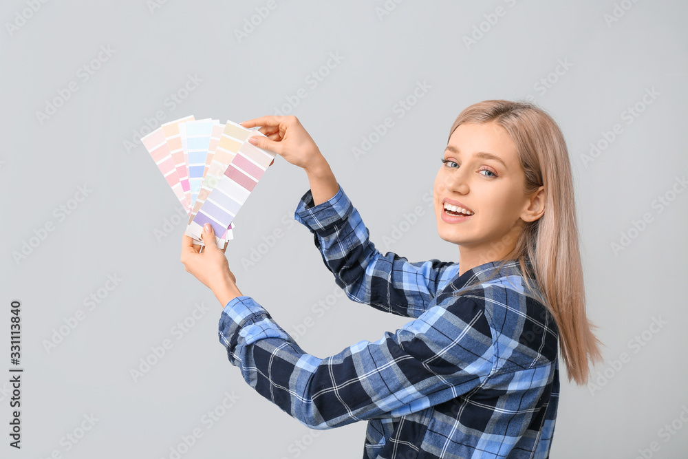 Young woman with color swatches on grey background