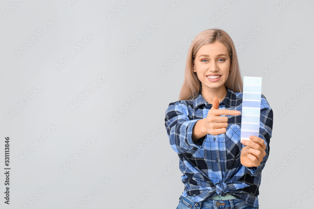 Young woman with color swatches on grey background