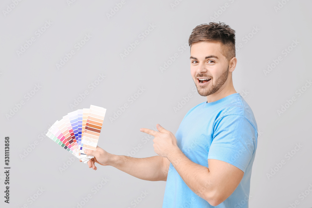 Young man with color swatches on grey background