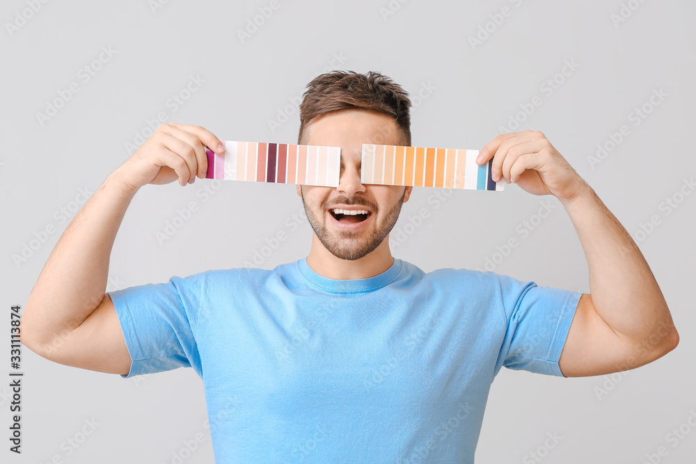 Young man with color swatches on grey background