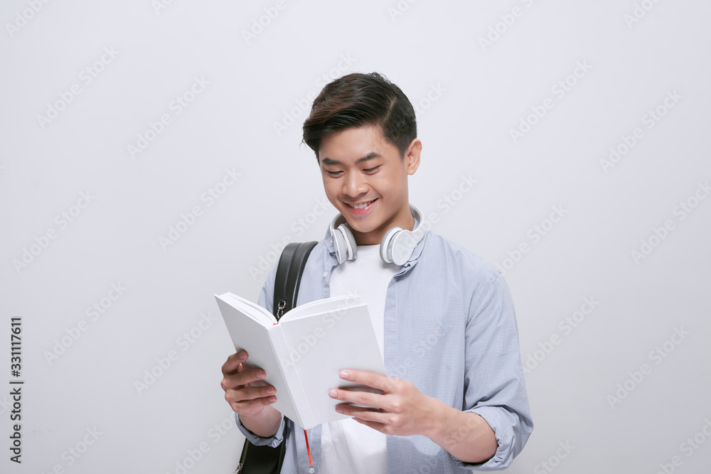 Waist-up portrait of Asian university student distracted from reading book and looking at camera wit