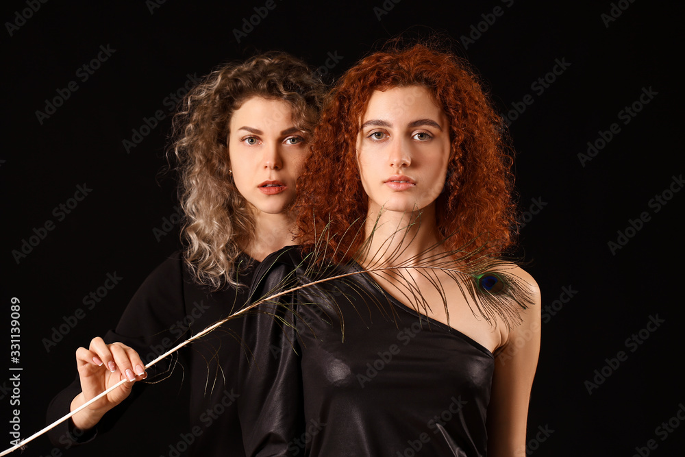 Beautiful young women with peacock feather on dark background