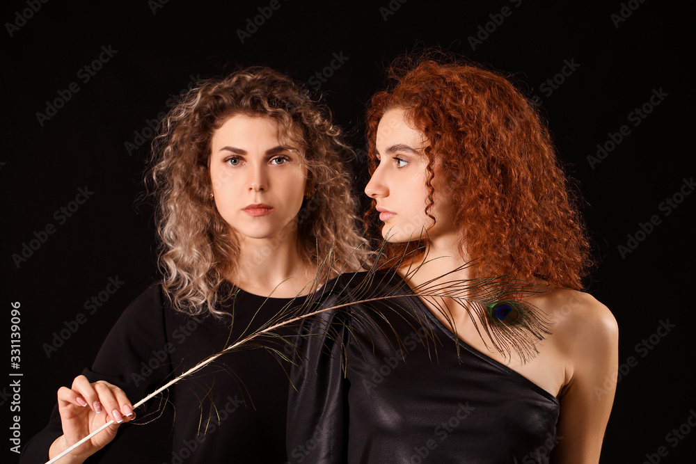 Beautiful young women with peacock feather on dark background