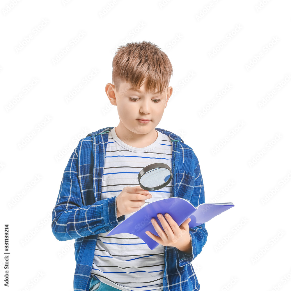 Cute little boy with magnifier and notebook on white background