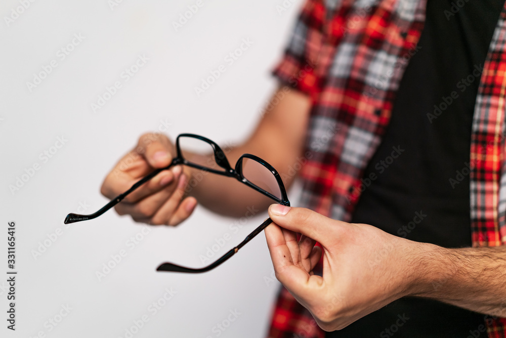 Males hand holding trendy eyeglasses isolated on white background. Glasses in black frame in mans 