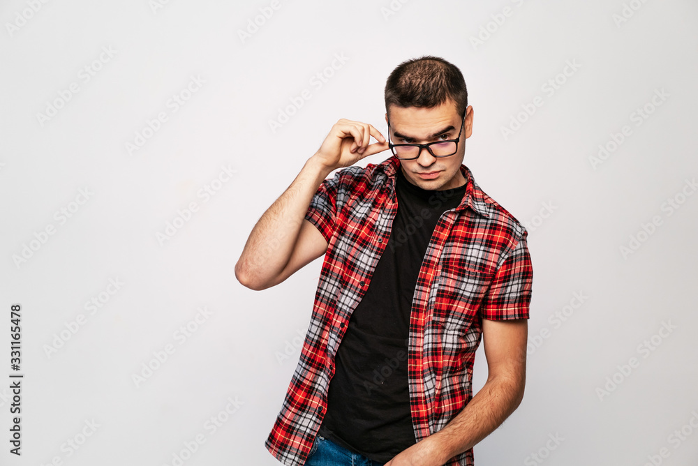 Close-up of young trendy guy with glasses smiling, white studio shot. A portrait of clever man in t-