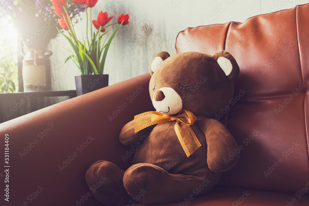 bear doll on sofa with flower in vase