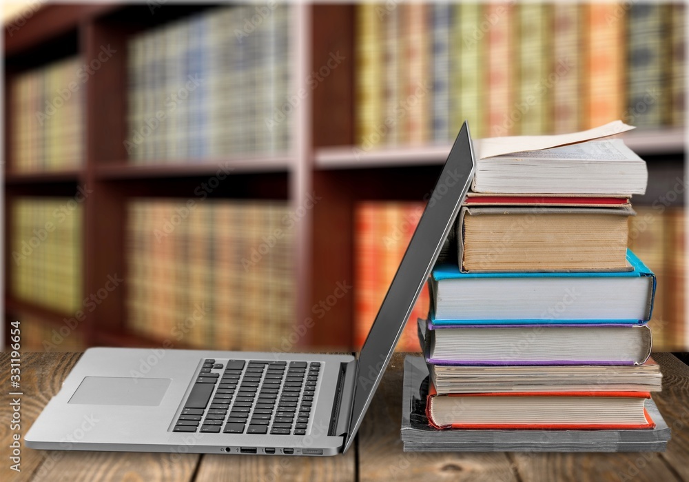 Stack of books with a modern laptop on a table