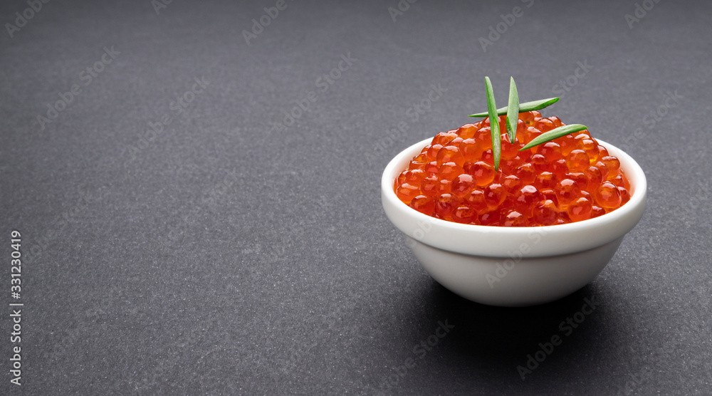 Red caviar on black stone background with copy space close-up