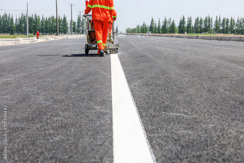 道路工人使用热熔划线机在沥青路面上画分界线