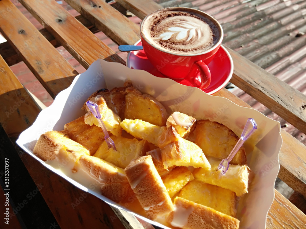 Cappuccino in a red coffee cup with butter toast on a wooden table