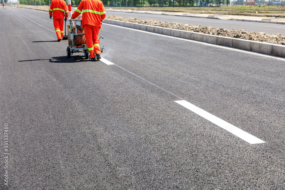 道路工人使用热熔划线机在沥青路面上画分界线