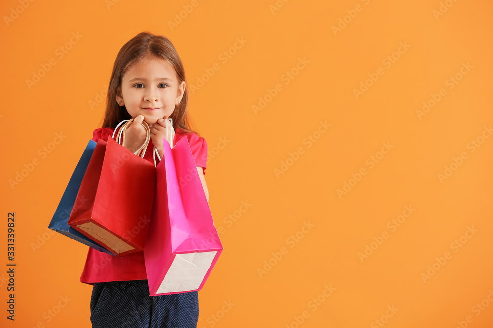 Cute little girl with shopping bags on color background