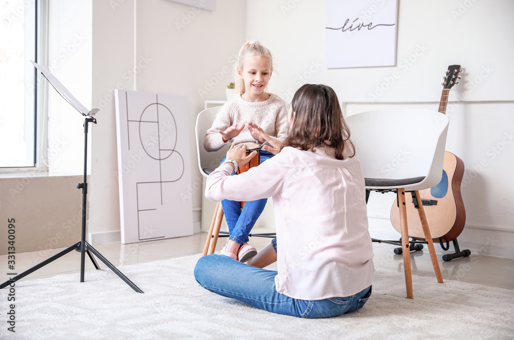 Private music teacher giving lessons to little girl at home