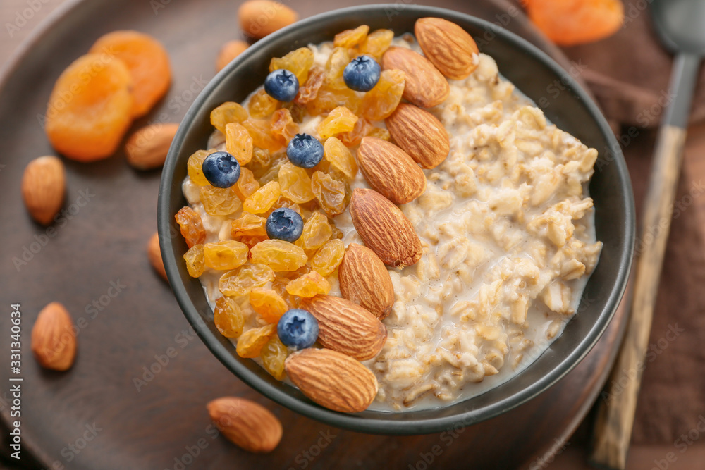 Bowl with tasty sweet oatmeal on table, closeup