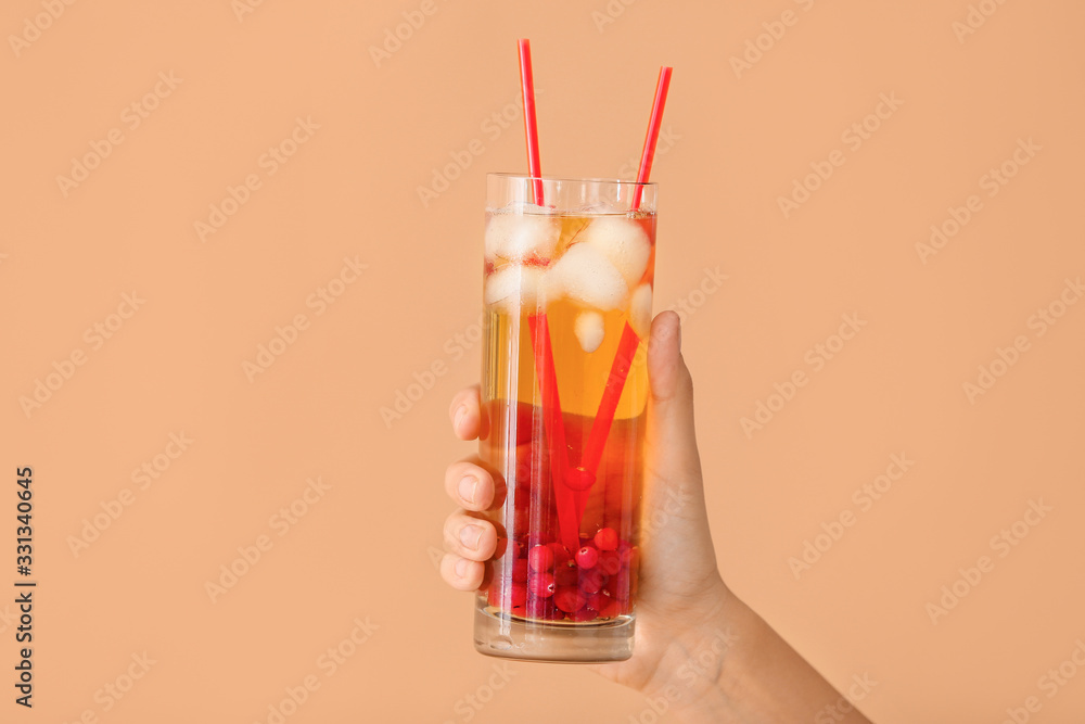 Female hand with cold tea in glass on color background