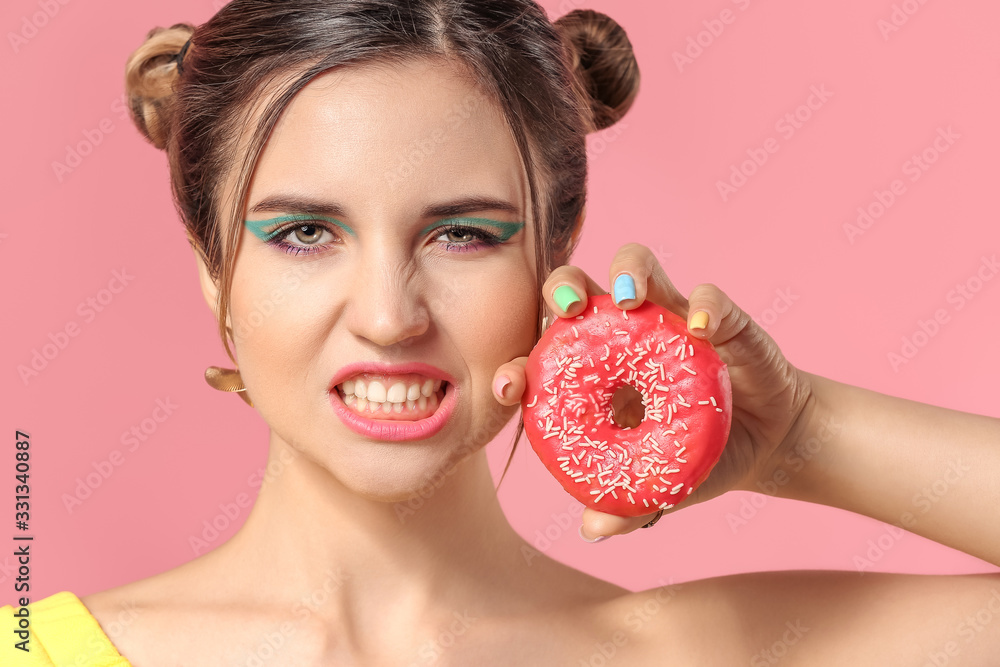 Young woman with beautiful manicure and donut on color background