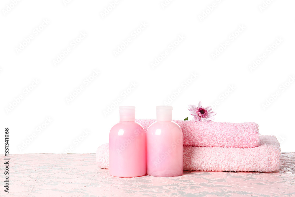 Shampoo and towels on table against white background