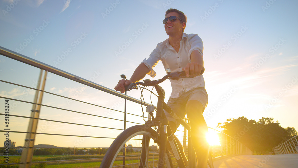 LENS FLARE: Carefree man enjoys a sunny summer evening by riding a bicycle.