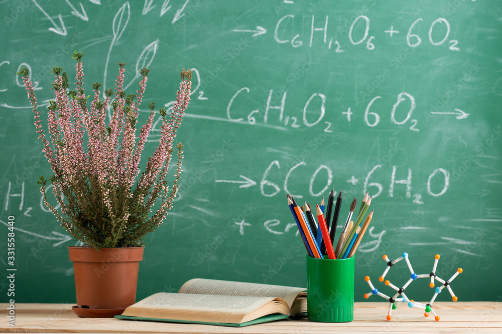 Education and sciences concept - bookand molecule model on the desk in the auditorium, photosynthesi