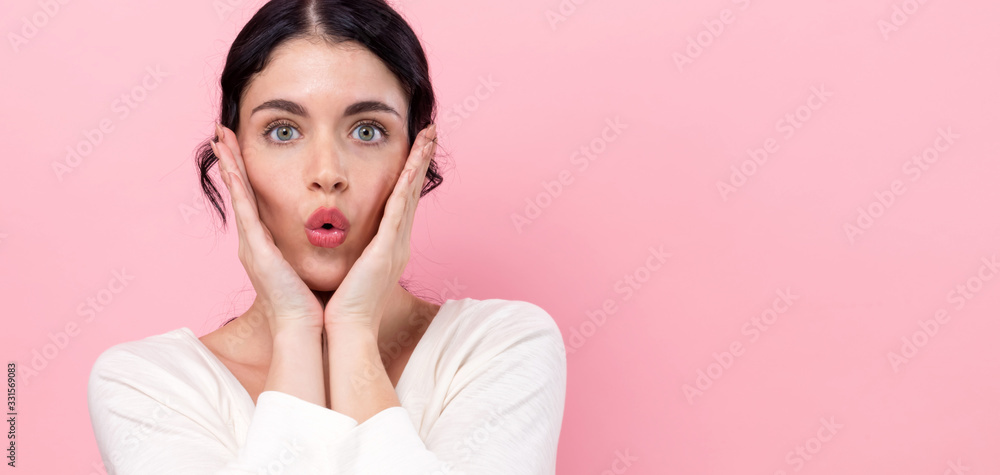 Surprised young woman posing on a pink background