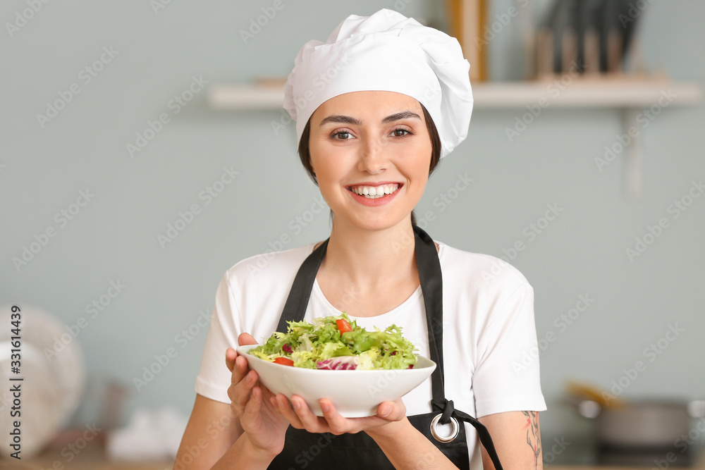 Female chef with tasty salad in kitchen