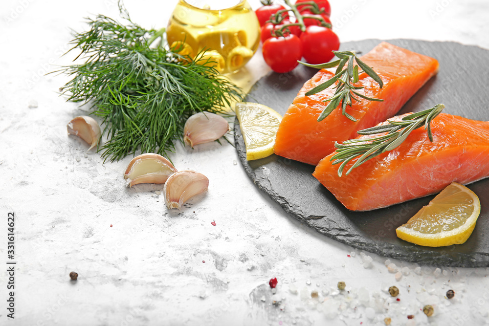 Raw salmon fillet with herbs, lemon and garlic on white background