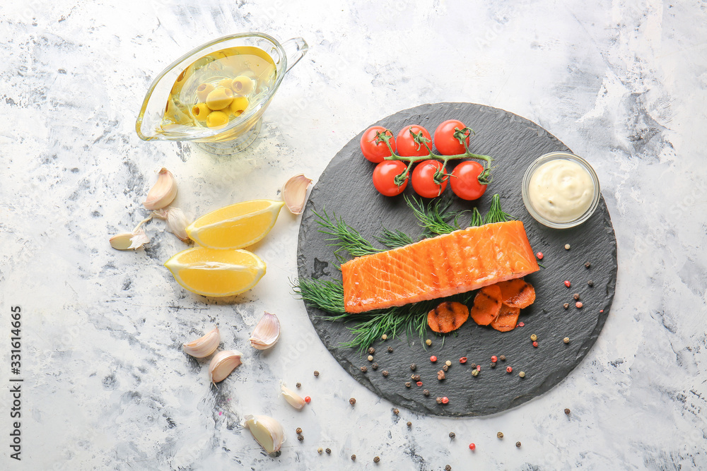 Cooked salmon fillet with vegetables, sauce and spices on white background