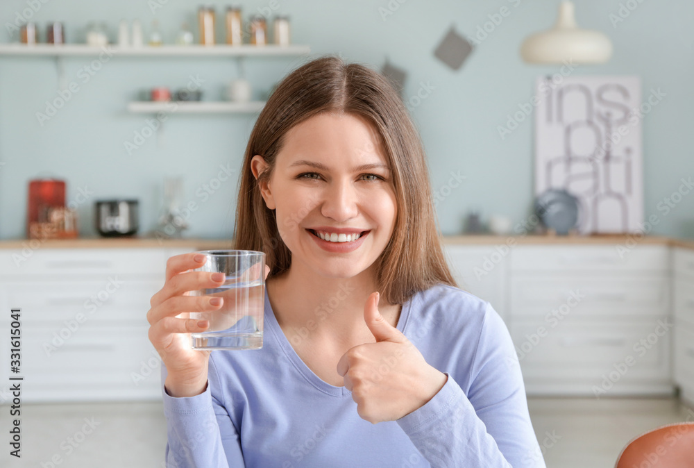 家里有一杯水，大拇指向上的漂亮年轻女人