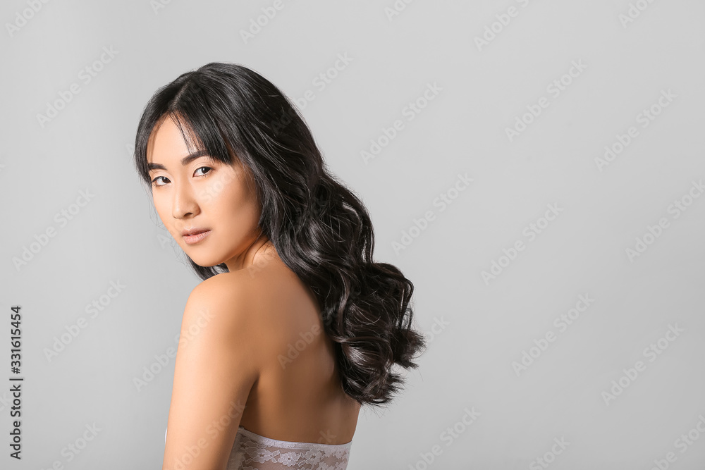 Young Asian woman with beautiful long hair on light background