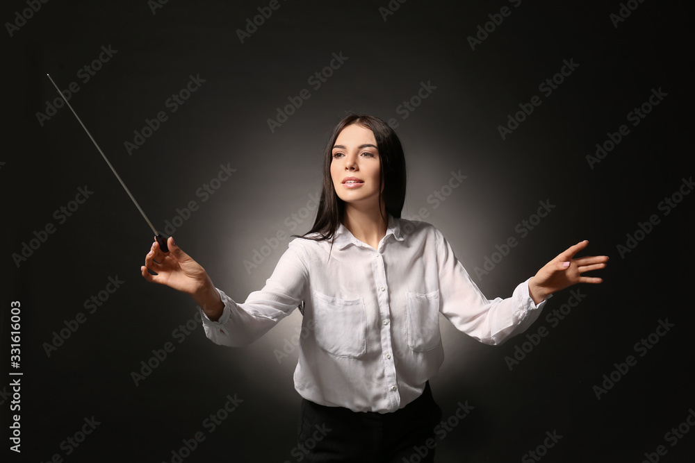 Young female conductor on dark background