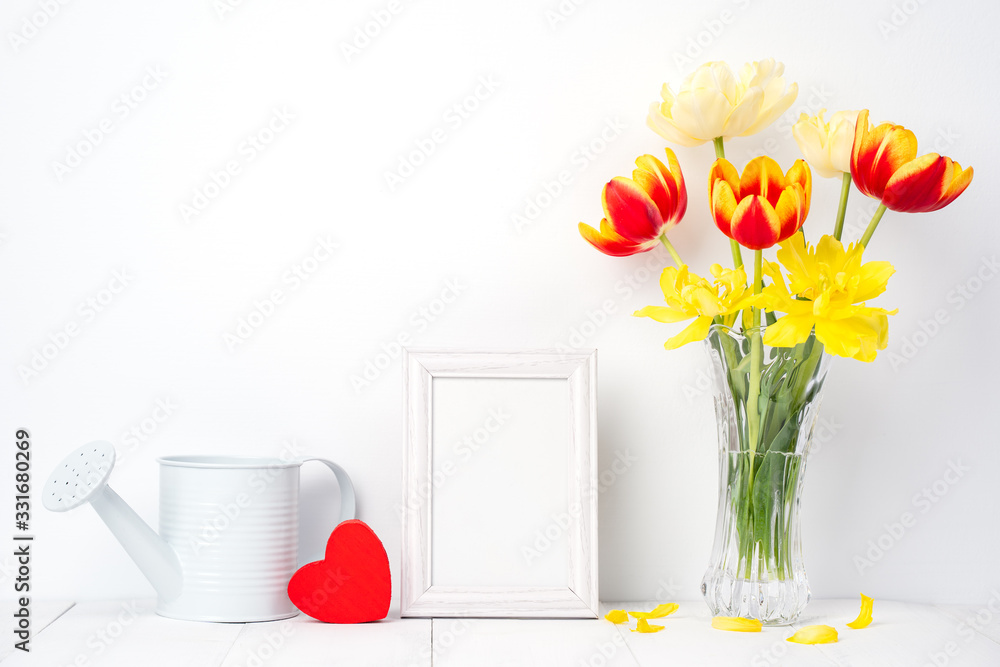 Tulip flower in glass vase with picture frame place on white wooden table background against clean w