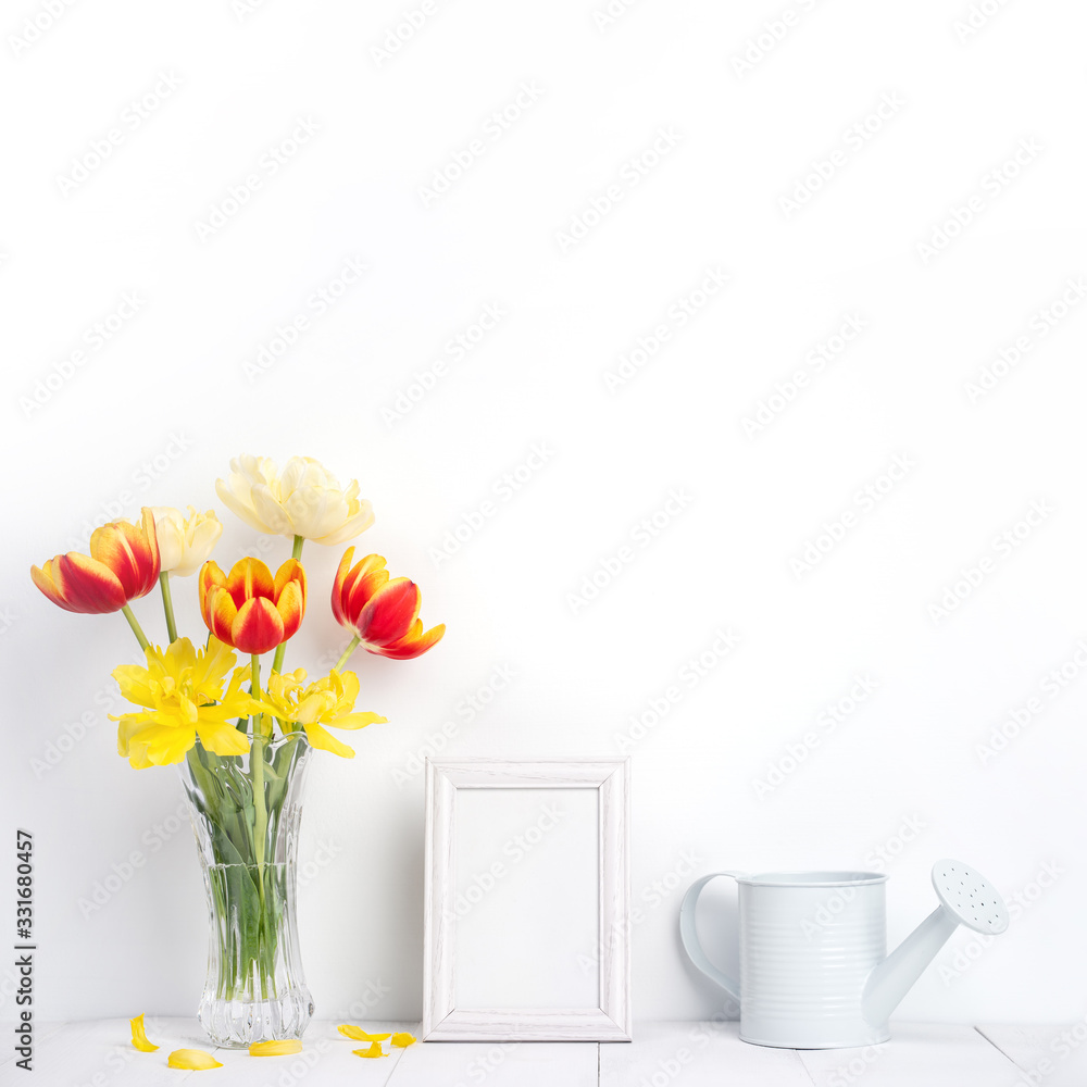 Tulip flower in glass vase with picture frame place on white wooden table background against clean w