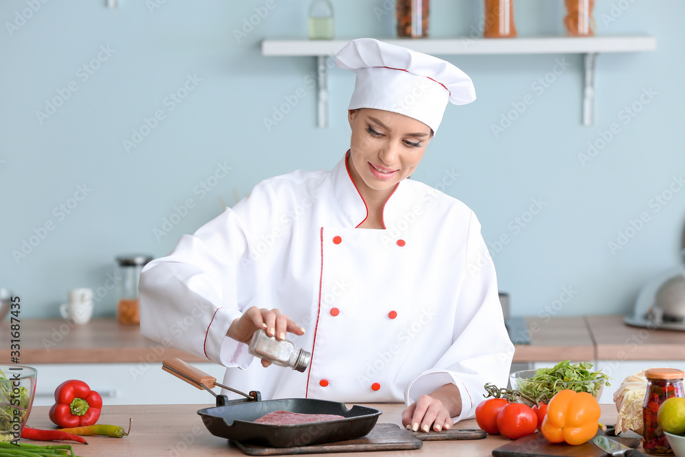 Female chef cooking meat in kitchen