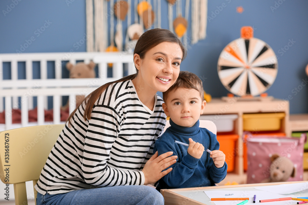 Nanny and cute little boy drawing at home