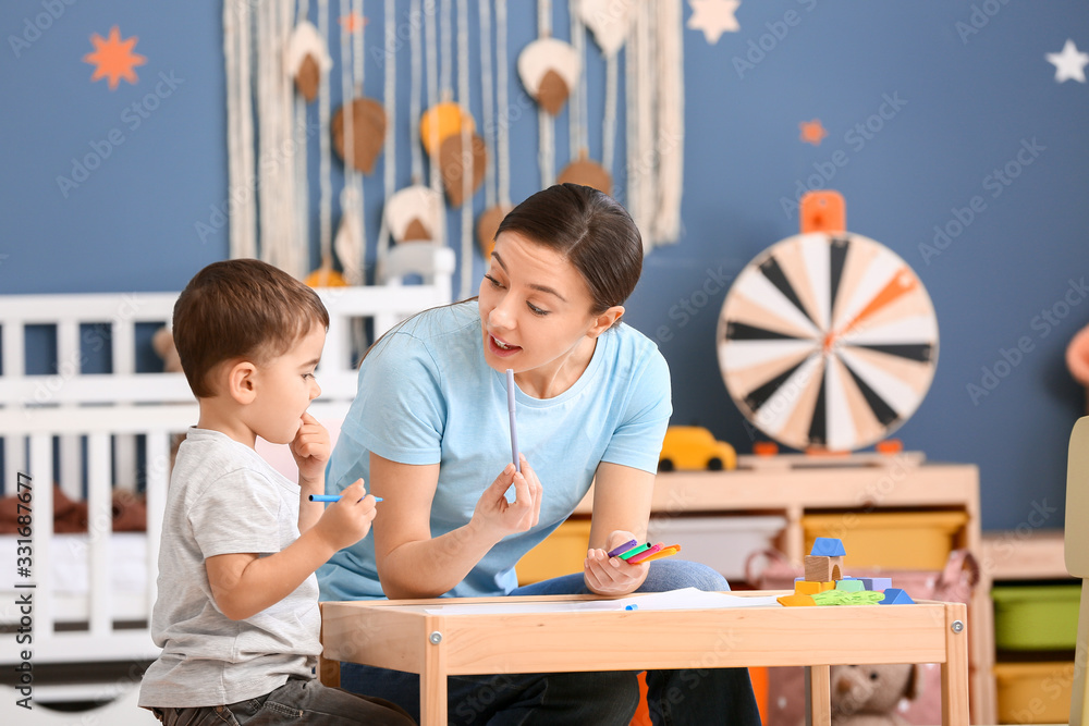 Nanny and cute little boy drawing at home