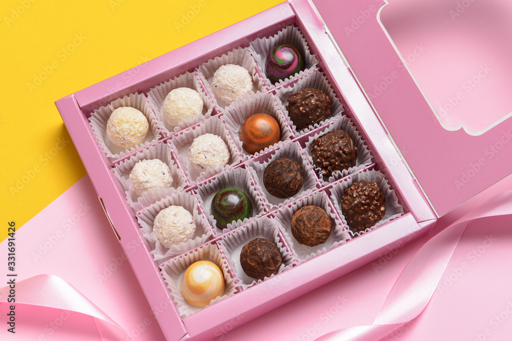 Box with delicious candies on color background