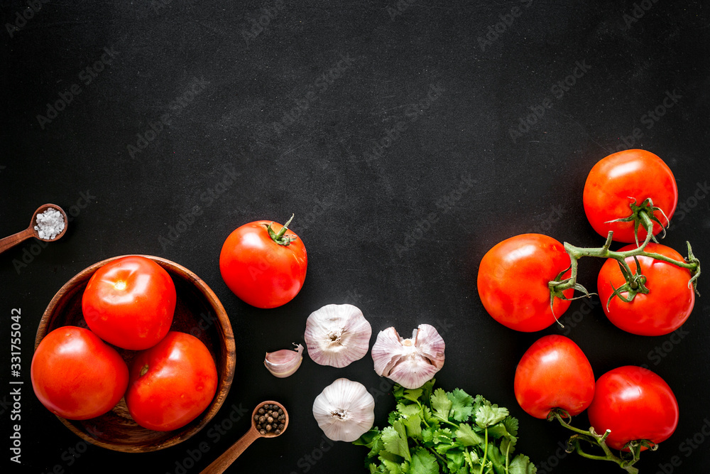 Tomatoes harvest. Vegetables near garlic, greenery and spices on black background top-down copy spac