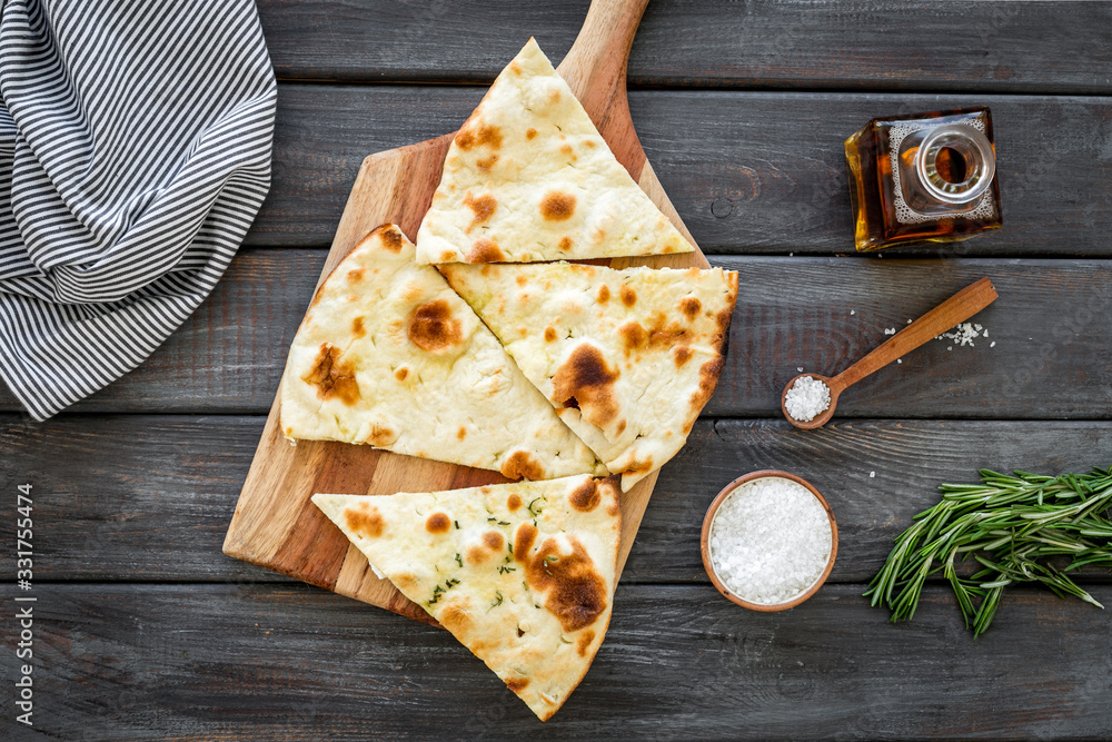 Italian focaccia with cheese and rosemary on dark wooden background top-down