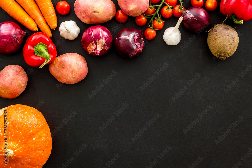 Set of autumn vegetables - potato, cucumber, carrot, greenery - on black background top-down copy sp