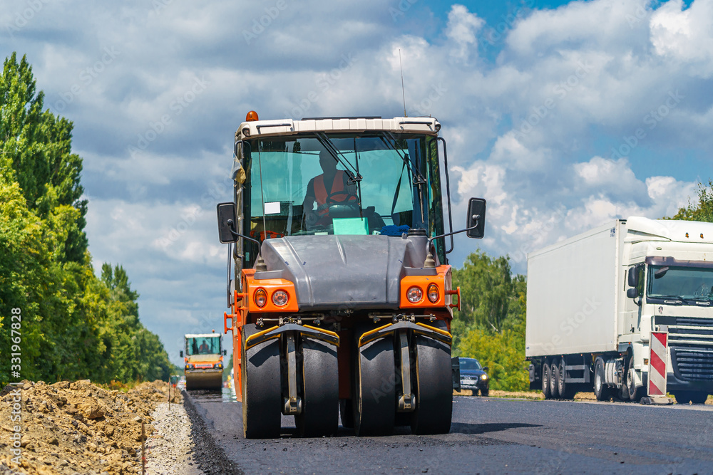 Road repair, compactor lays asphalt. Heavy special machines. Asphalt paver in operation. Side view. 