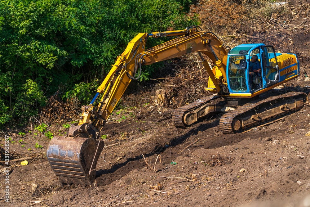 Yellow backhoe with hydraulic piston arm. Heavy machine for excavation in construction site.