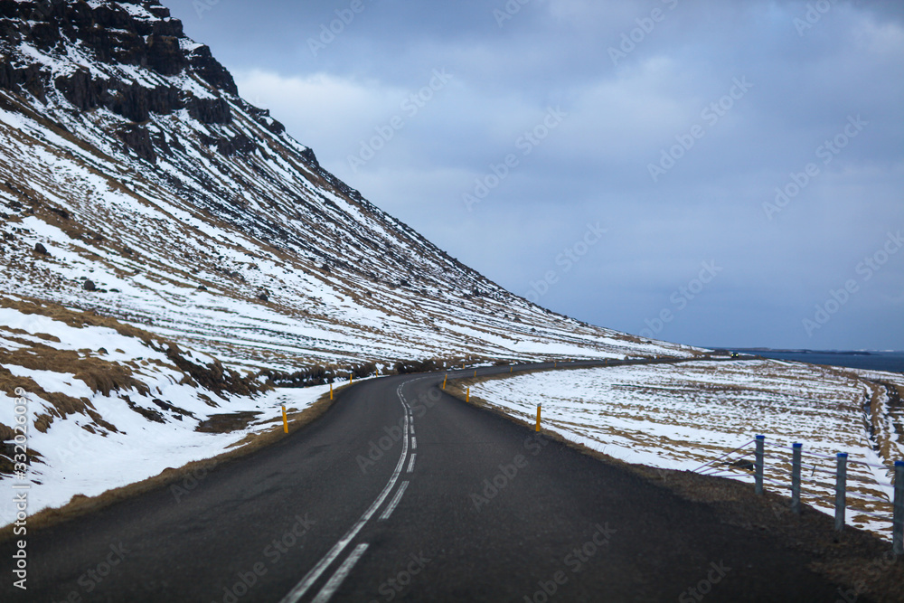 冰岛冬季景观中的道路。沥青道路，一侧满是雪