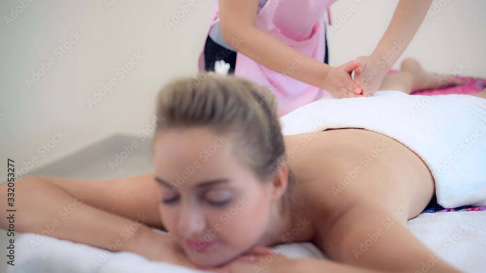 Woman gets back massage spa by massage therapist.