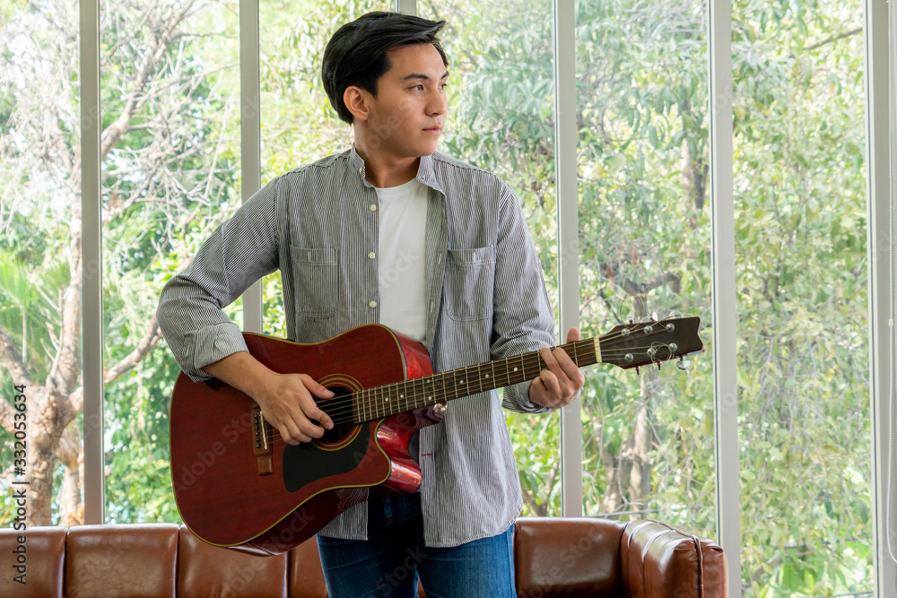 Young guitar player holding his guitar at home.