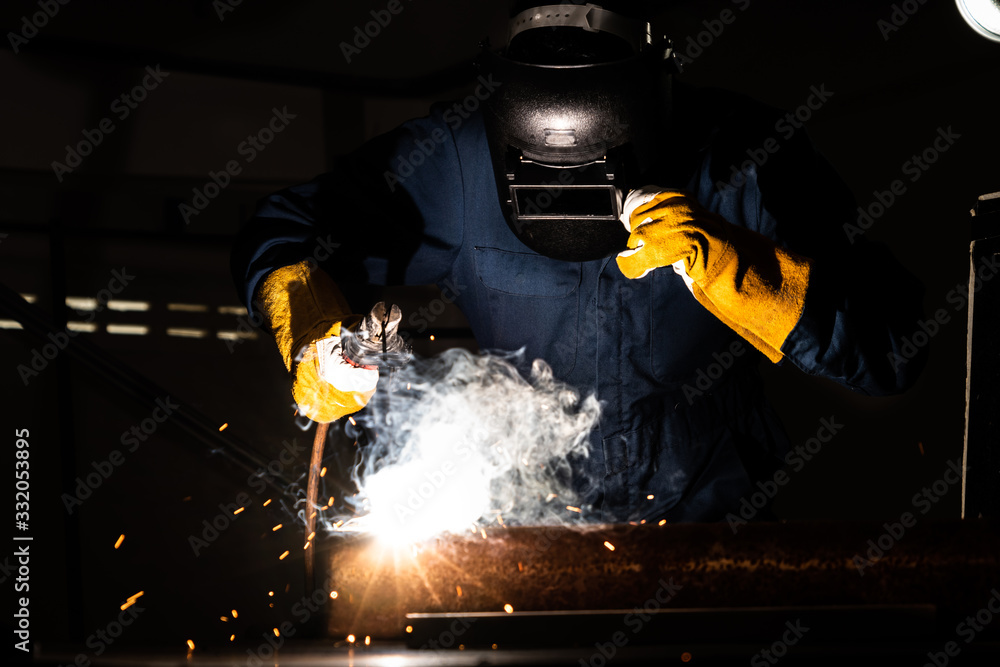 Metal welder working with arc welding machine.